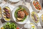 Top-down view of Mediterranean dishes including salads and seafood on an elegant table setting.