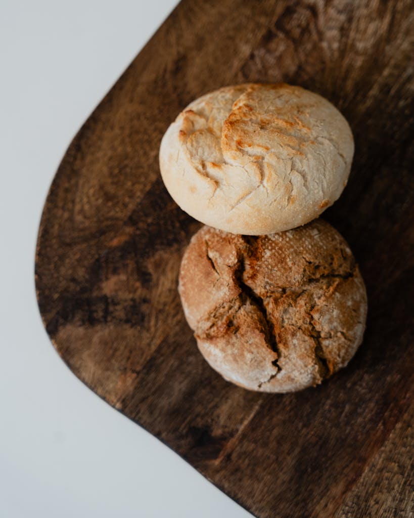Top-down view of two rustic artisan bread loaves on a wooden board.