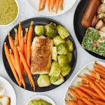 Top view of a healthy meal featuring baked fish, carrots, and Brussels sprouts.