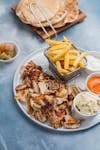 Top view of a Middle Eastern meal with grilled chicken, fries, and dips, perfect for lunch or dinner.