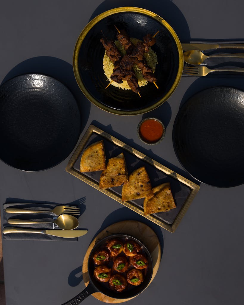 Top view of a sophisticated dining setup with skewers, appetizers, and elegant tableware.