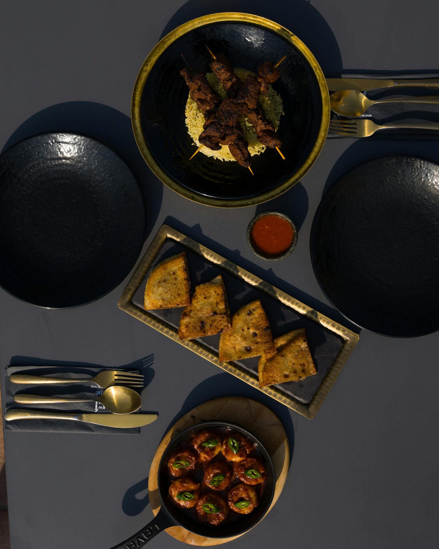 Top view of a sophisticated dining setup with skewers, appetizers, and elegant tableware.